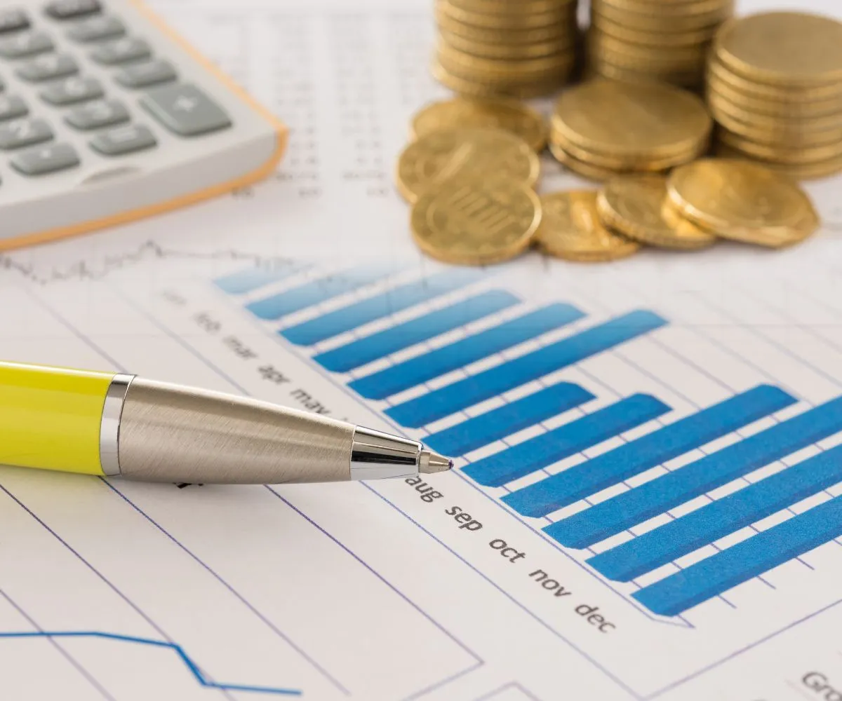 Gold coins stacked beside financial reports representing business financial consulting