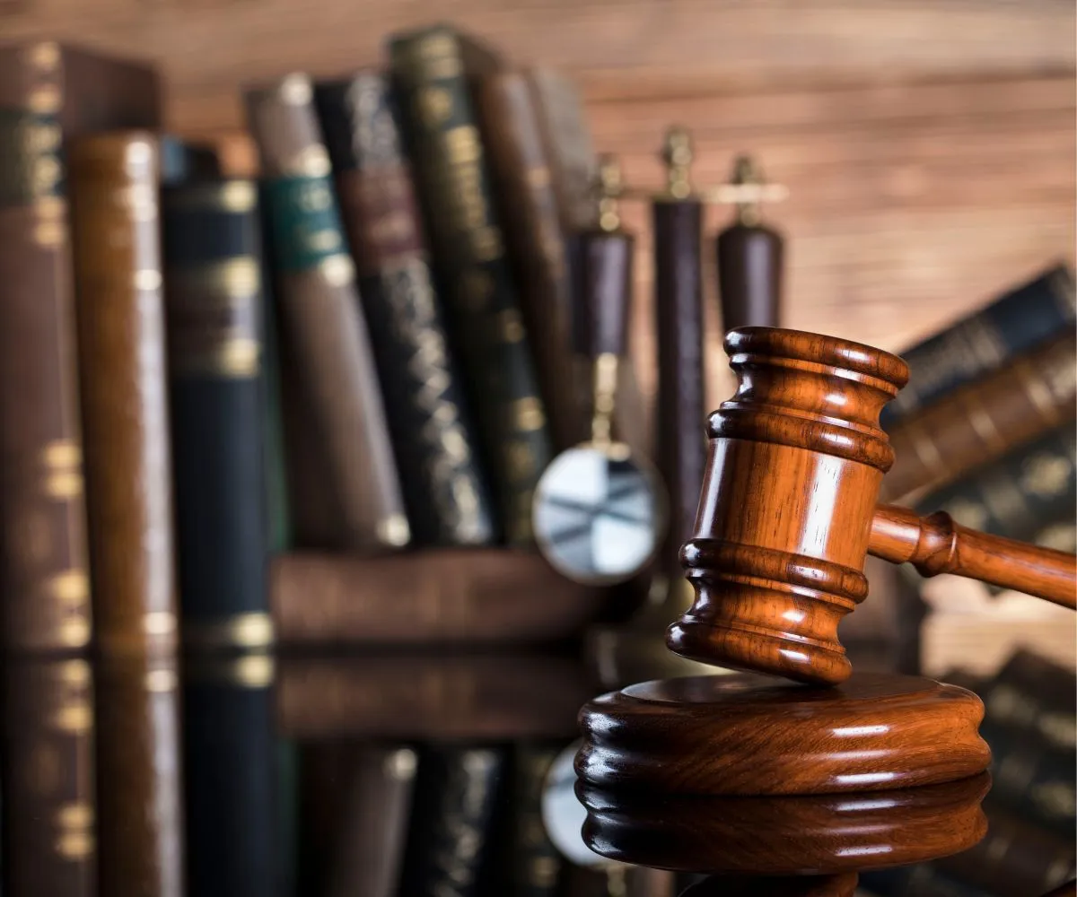Brass scales of justice on a desk beside legal compliance books